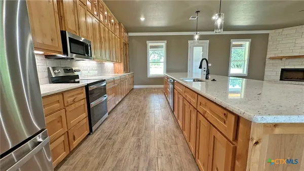 a large kitchen with granite countertop a large counter top space a sink stainless steel appliances and cabinets