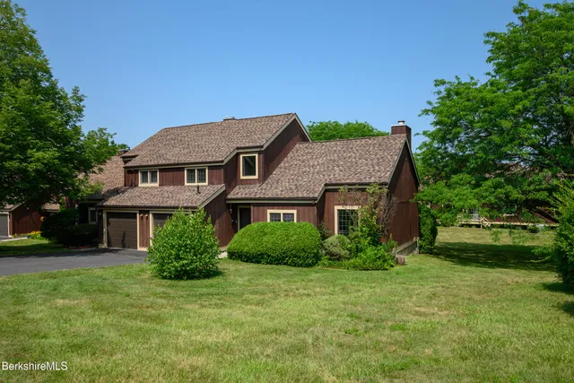 a brick house with a big yard plants and large trees