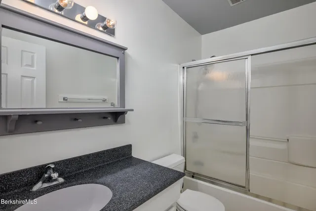 a bathroom with a granite countertop sink mirror vanity and toilet