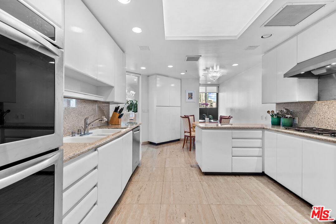 10490 Wilshire Boulevard, Unit 1206 Los Angeles, CA 90024 - Photo 19 of 44 a large white kitchen with kitchen island a sink white cabinets and stainless steel appliances
