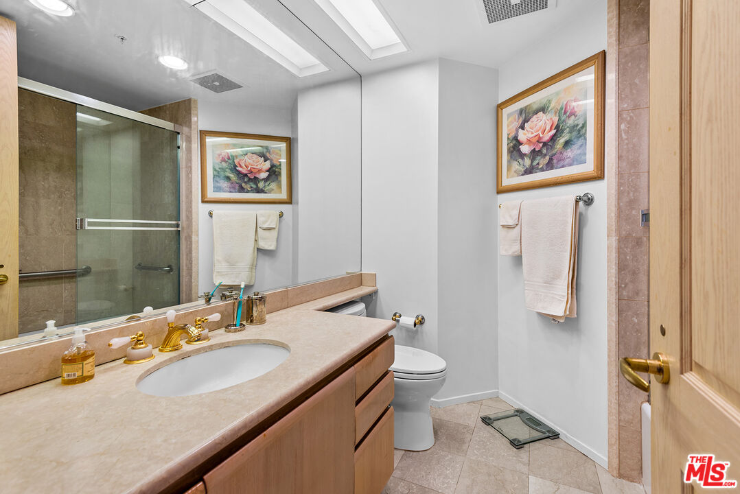 10490 Wilshire Boulevard, Unit 1206 Los Angeles, CA 90024 - Photo 30 of 44 a bathroom with a granite countertop sink toilet and shower