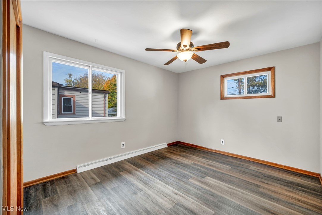 10927 Granger Road Cleveland, OH 44125 - Photo 6 of 33 Spare room with a baseboard heating unit, plenty of natural light, wood finished floors, and a ceiling fan
