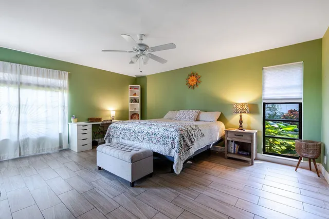 a bedroom with a bed a dresser with wooden floor