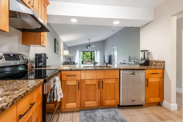a kitchen with stainless steel appliances granite countertop a refrigerator a stove and a sink with wooden floor