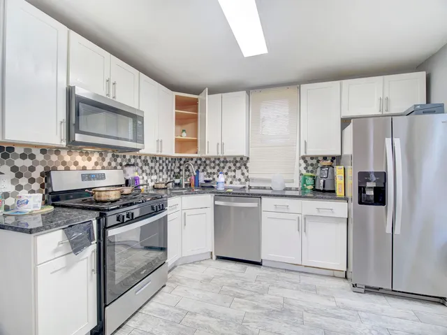a kitchen with granite countertop a sink stove and refrigerator