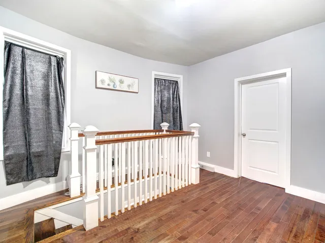 a view of a hallway with wooden floor and windows
