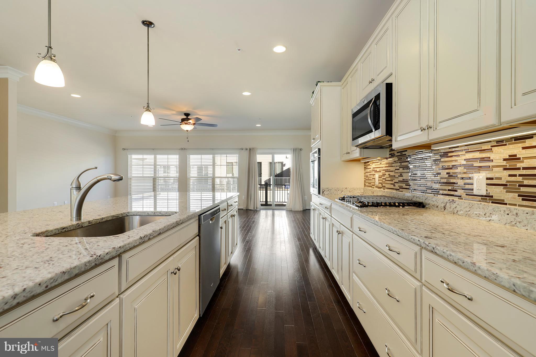 a large kitchen with granite countertop a large stove a sink dishwasher and white cabinets with wooden floor