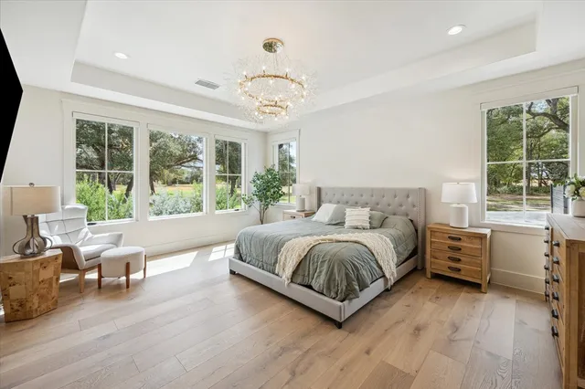 a spacious bedroom with a large bed and a chandelier