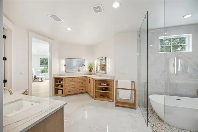 a large en suite bathroom with a double vanity sink a large mirror and a bathtub