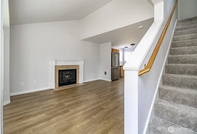 a view of an empty room with wooden floor and a fireplace