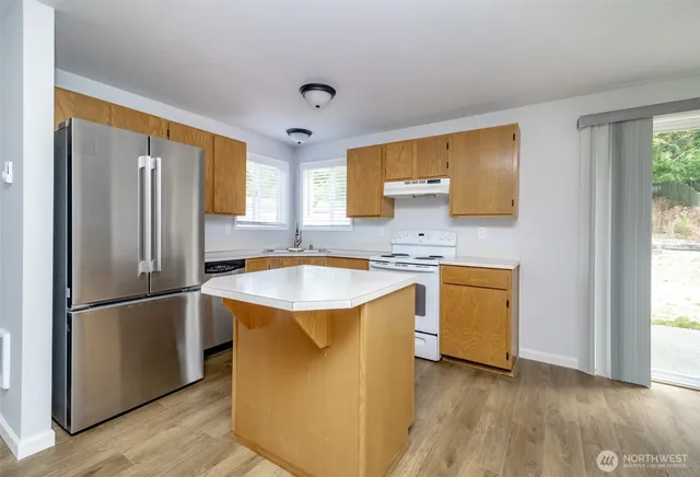 a kitchen with kitchen island granite countertop a sink appliances cabinets and a counter top space