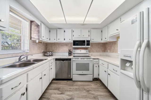 a kitchen with cabinets appliances a sink and a window