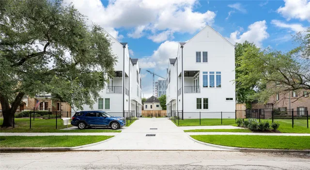 a view of a white house with a yard and table and chairs under an umbrella
