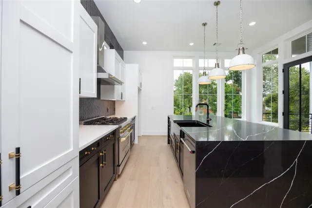 a kitchen with stainless steel appliances a sink a stove and white cabinets