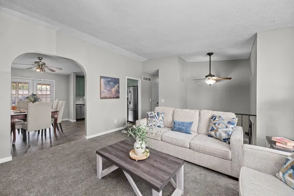 a living room with furniture a dining table and a chandelier