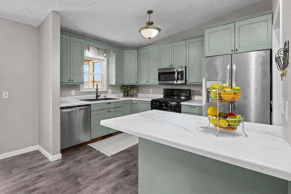 a kitchen with stainless steel appliances a sink a stove a refrigerator cabinets and a window