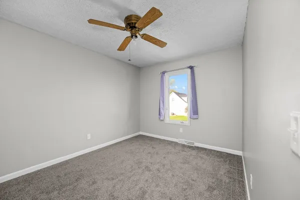 an empty room with a window and a ceiling fan