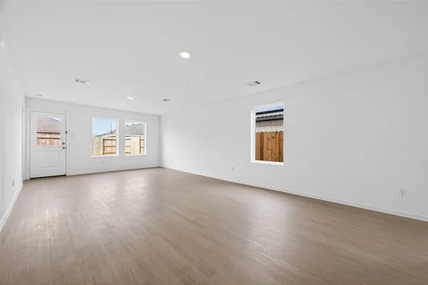 a view of an empty room with a window and wooden floor