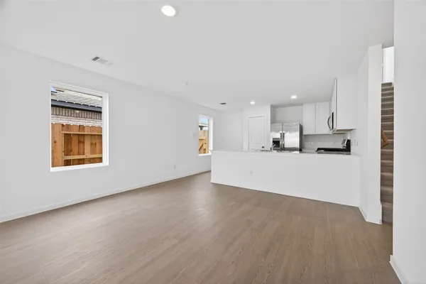 a view of kitchen with kitchen island wooden floor center island and stainless steel appliances