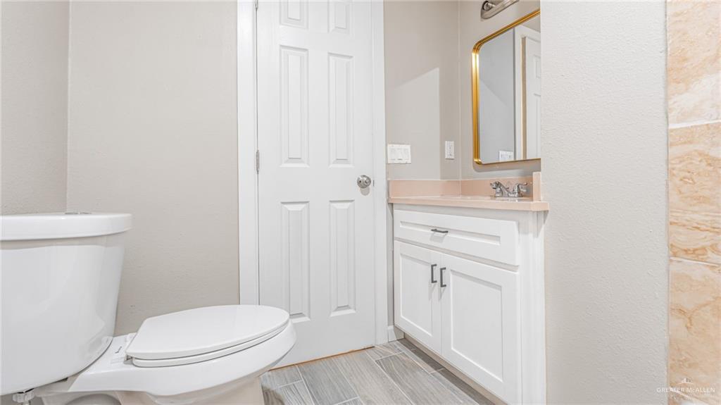 712 Toronto Avenue, Unit 7 McAllen, TX 78503 - Photo 9 of 12 a bathroom with a toilet a sink and mirror