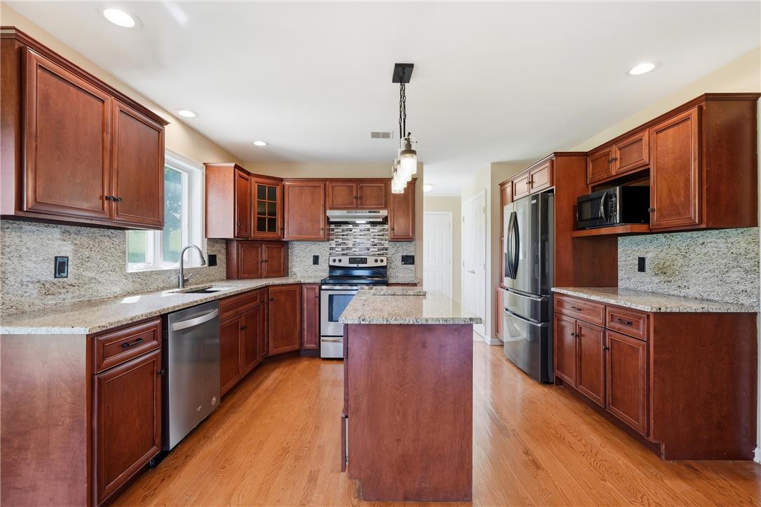 590 Fehr Road Nazareth, PA 18064 - Photo 18 of 79 Rich wood cabinetry and stone countertops anchor this central kitchen space with matching hardwood floors.
