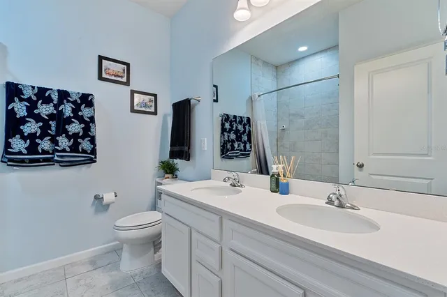 a bathroom with double vanity sinks a toilet a mirror and shower