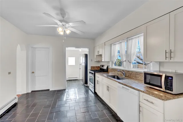 a kitchen with kitchen island granite countertop a sink a counter top space cabinets and stainless steel appliances