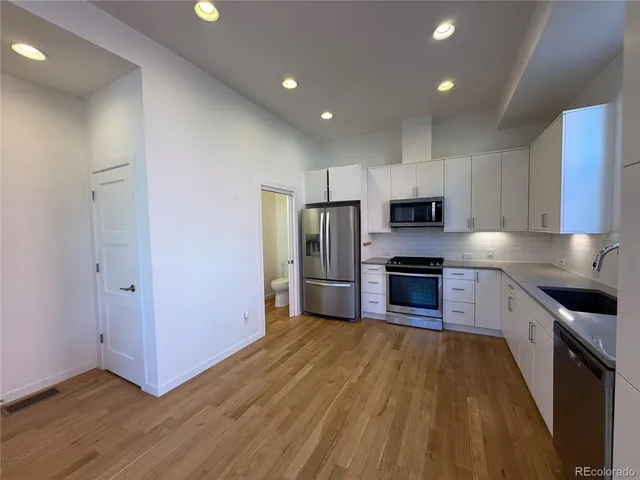 a kitchen with wooden floors and stainless steel appliances