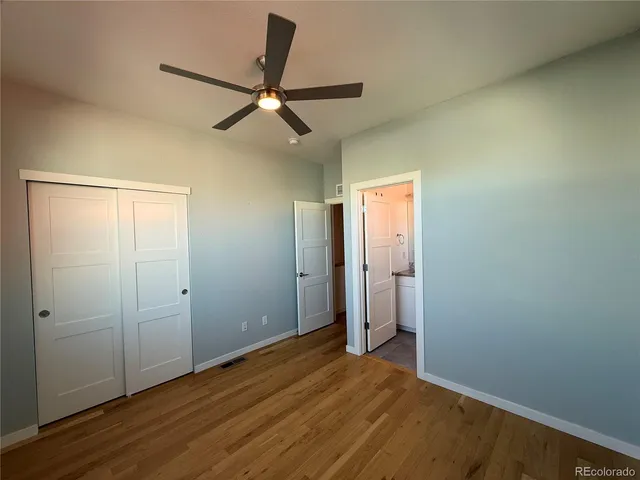an empty room with closet and a ceiling fan