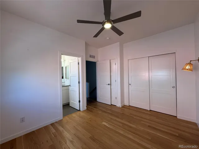 an empty room with wooden floor fan and windows