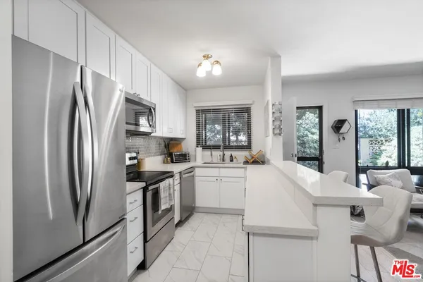 a kitchen with white cabinets and stainless steel appliances