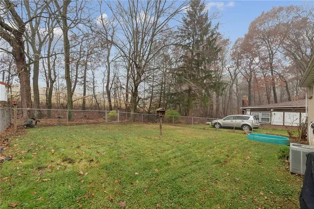 a view of a white house in front of a big yard with large trees