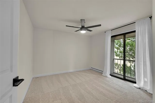 an empty room with windows and fan