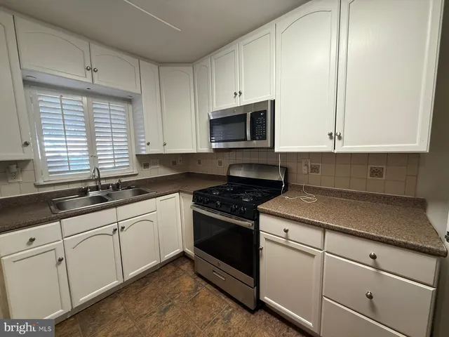 a kitchen with granite countertop white cabinets and white appliances