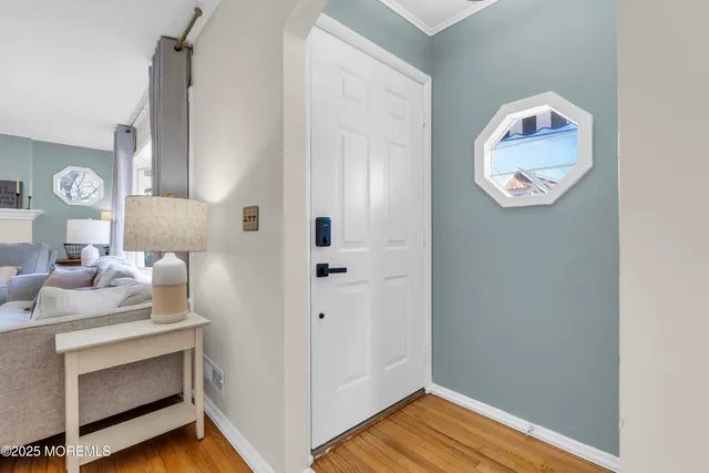 a view of a hallway to a room with wooden floor and cabinet