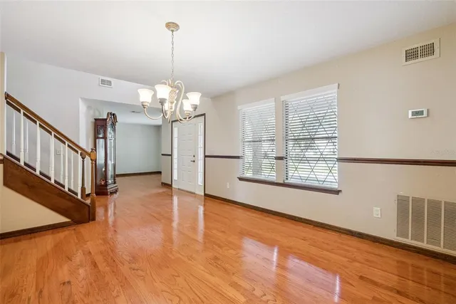 a view of a room with wooden floor chandelier and windows