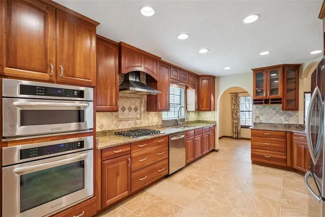 a kitchen with stainless steel appliances granite countertop wooden cabinets a stove and a sink