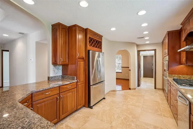 a kitchen with stainless steel appliances granite countertop a refrigerator and a stove top oven