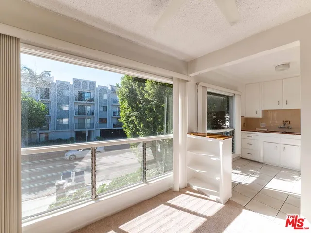 a open kitchen with granite countertop a refrigerator and white cabinets