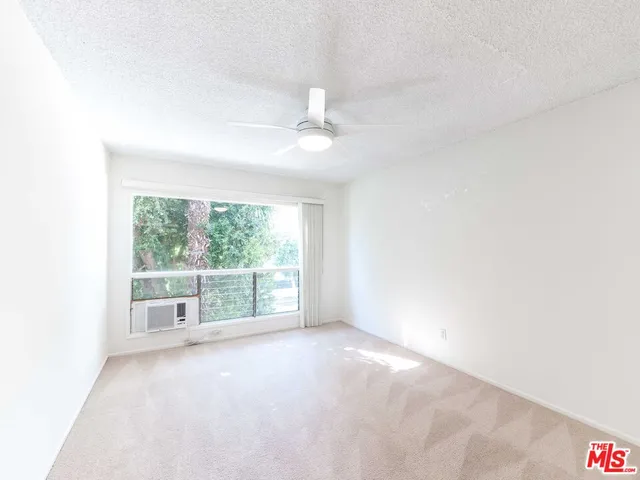 an empty room with windows and ceiling fan
