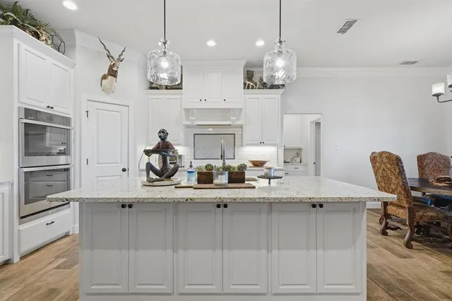 a kitchen with kitchen island granite countertop a sink cabinets and stainless steel appliances