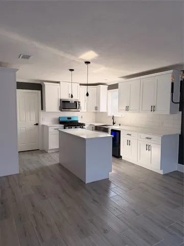 a large kitchen with stainless steel appliances kitchen island a cabinets and wooden floor
