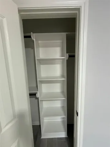 a view of an empty room with wooden floor and a fireplace