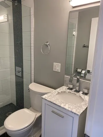 a bathroom with a granite countertop toilet sink and mirror