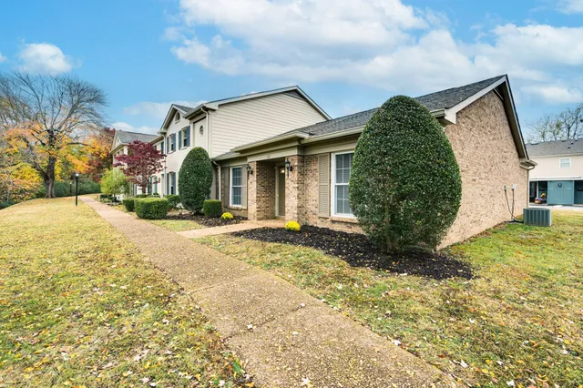 a view of a white house with a yard and plants