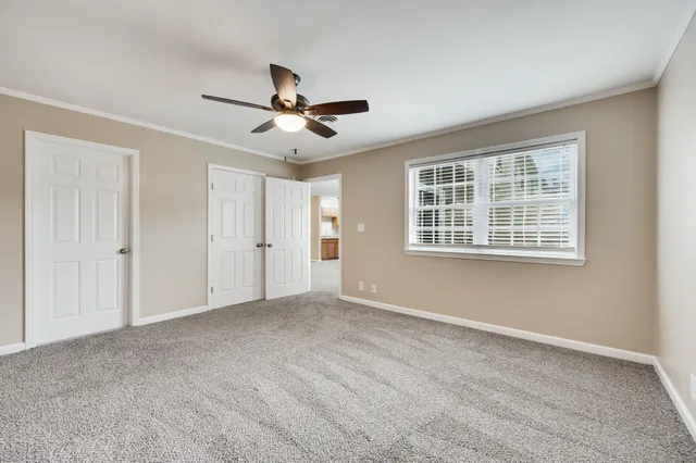 an empty room with closet and a ceiling fan
