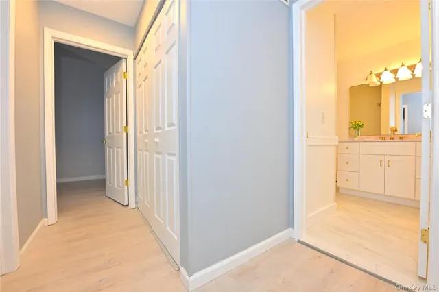 a view of a hallway with wooden floor and a bathroom