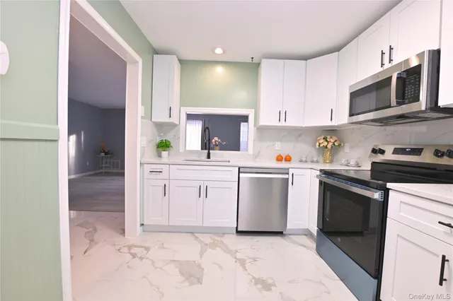 a kitchen with white cabinets and appliances