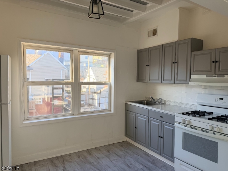 324 Summer Avenue, Unit 3 Newark, NJ 07104 - Photo 3 of 12 a kitchen with wooden cabinets and a stove top oven