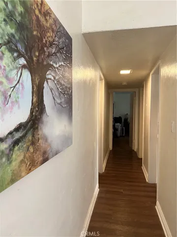 a view of a hallway with wooden floor and a living room